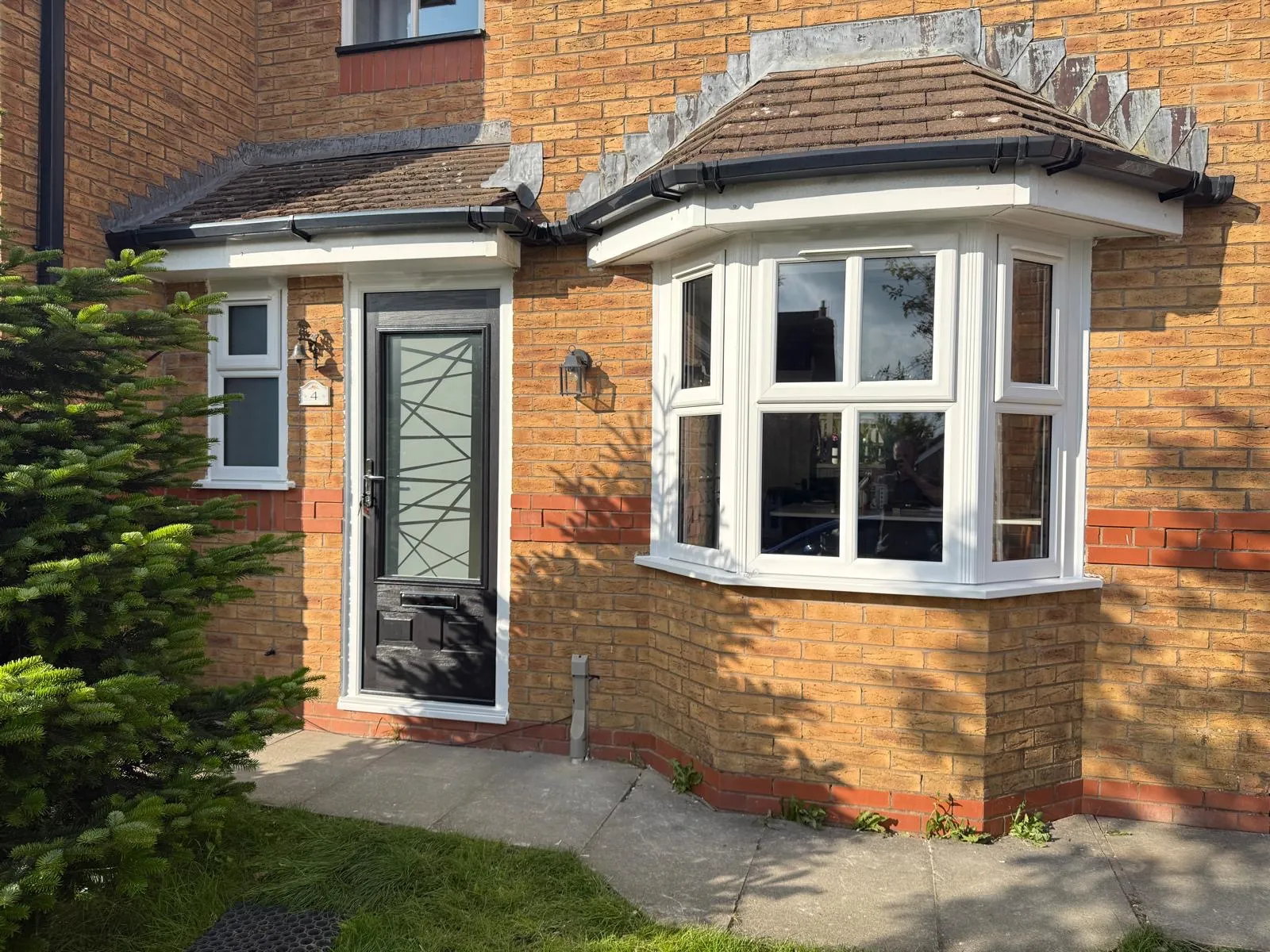 Grey composite front door with decorative glass panels fitted to a semi-detached home with bay window.