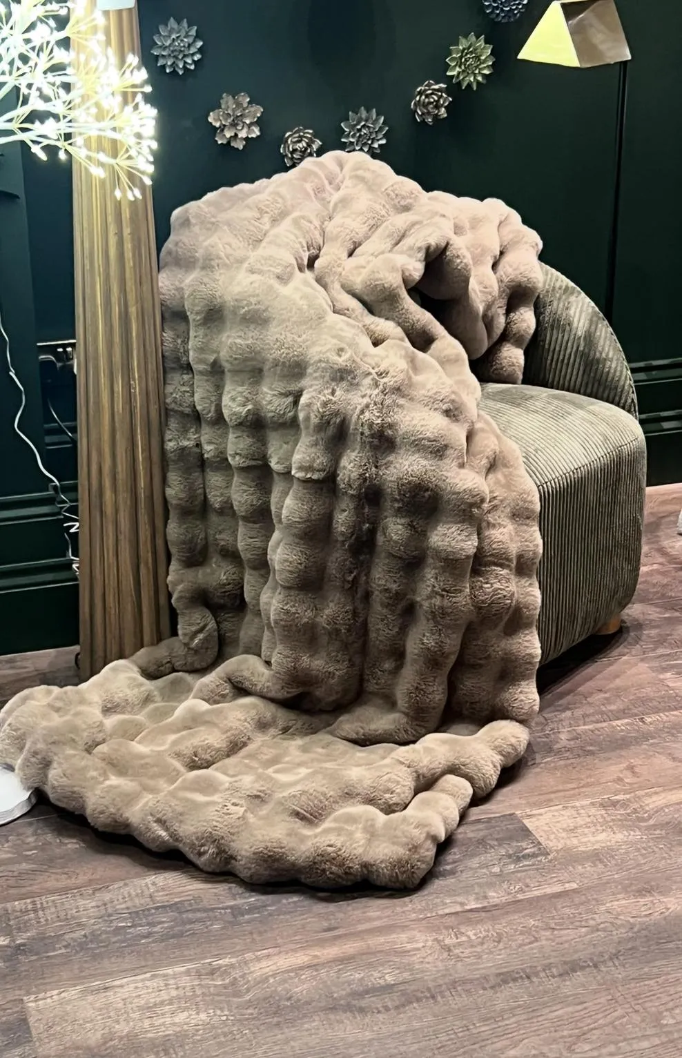 A textured beige throw blanket draped over a ribbed armchair in a room decorated with snowflake ornaments.