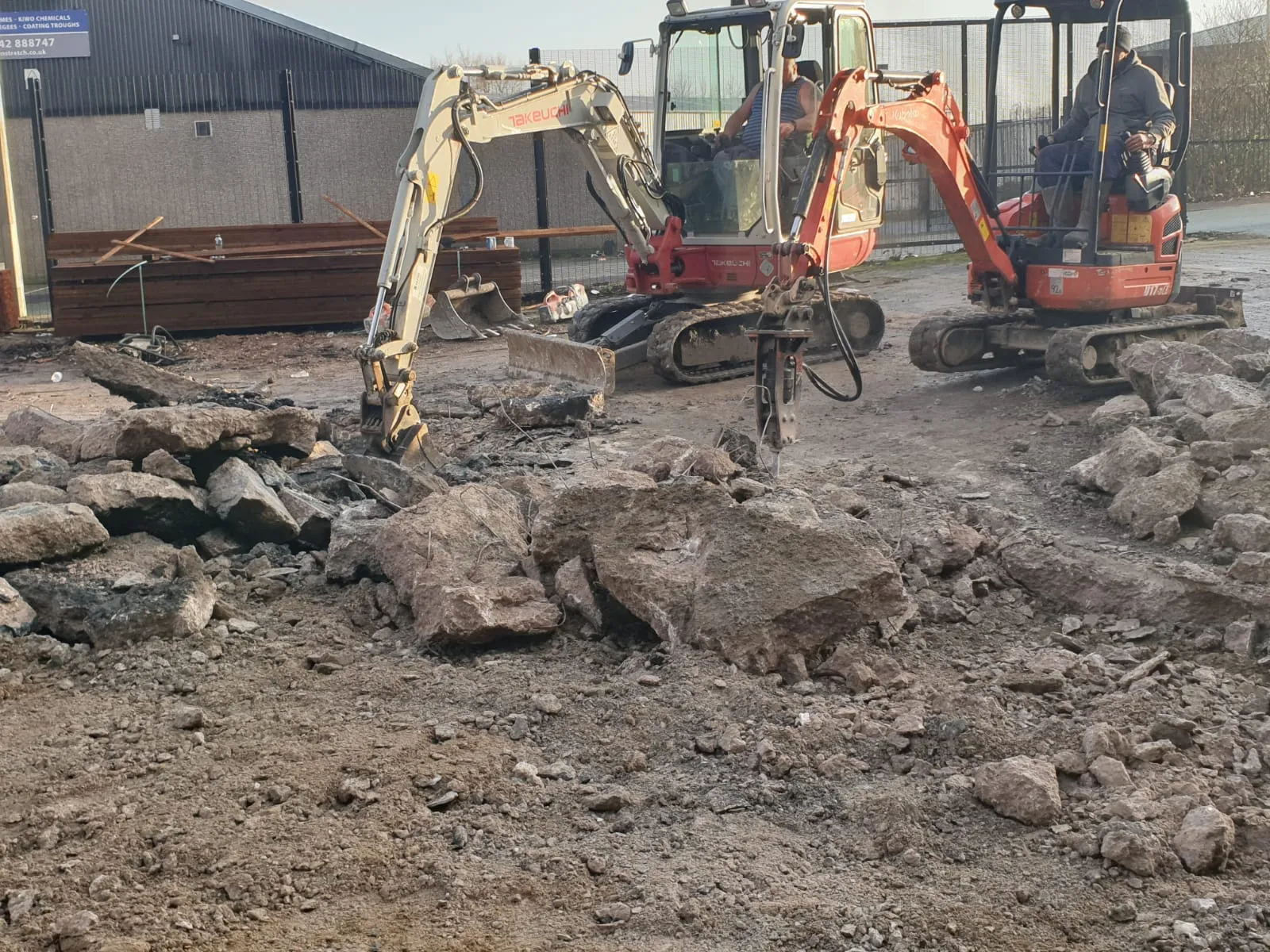 Excavators working on groundworks site with rocks and debris