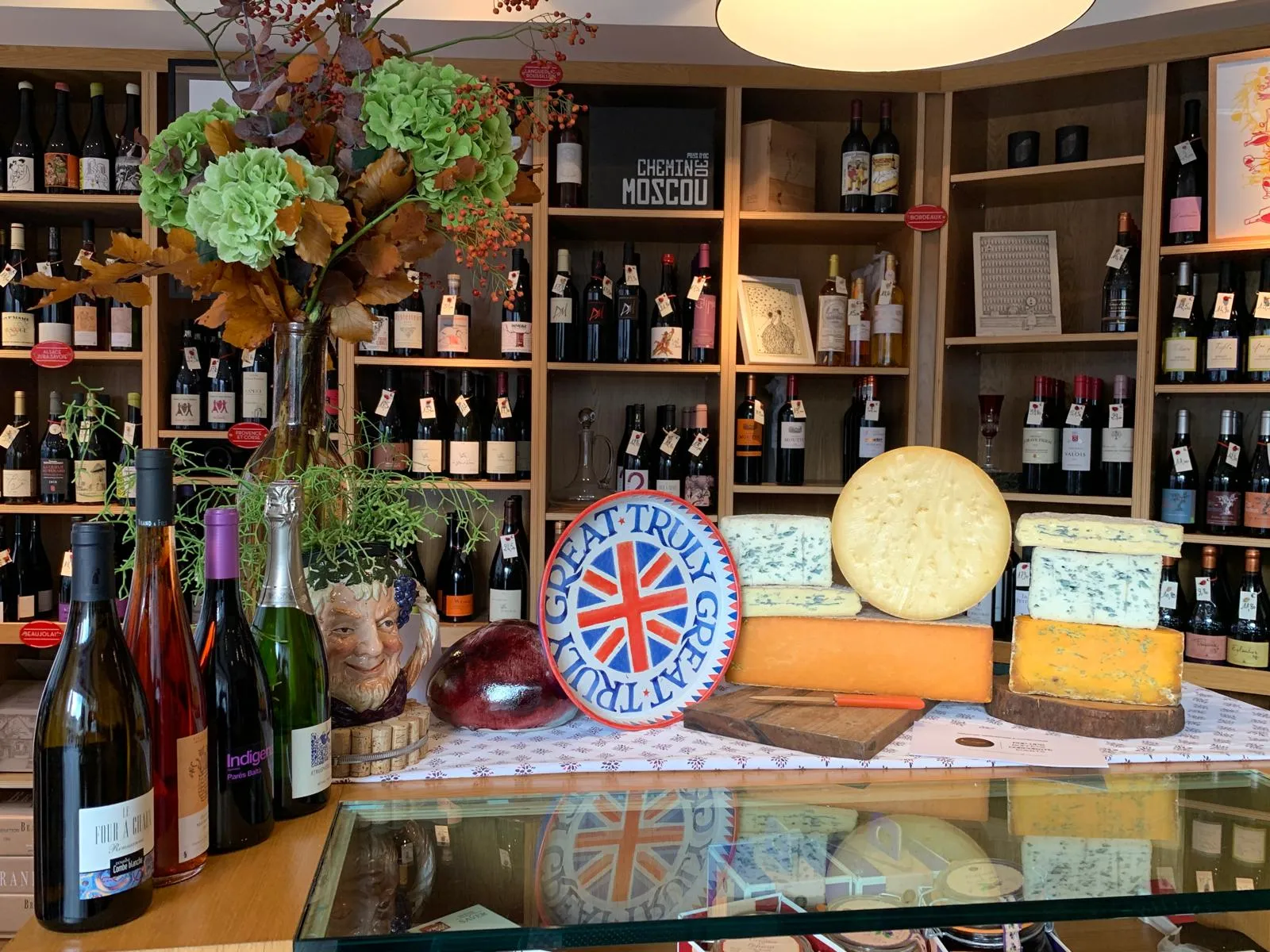 Pop-up event in a wine shop with extensive wine selection and British cheese display featuring aged cheddars and artisanal varieties