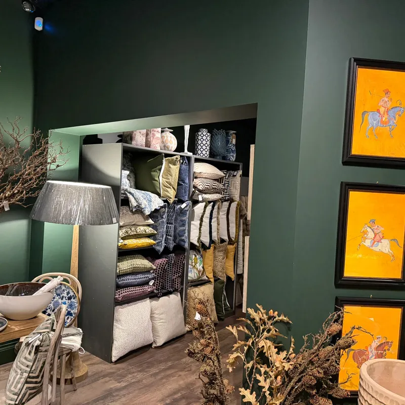 Sophisticated boutique interior with elegant wooden shelving displaying curated home décor, candles, and artisan accessories