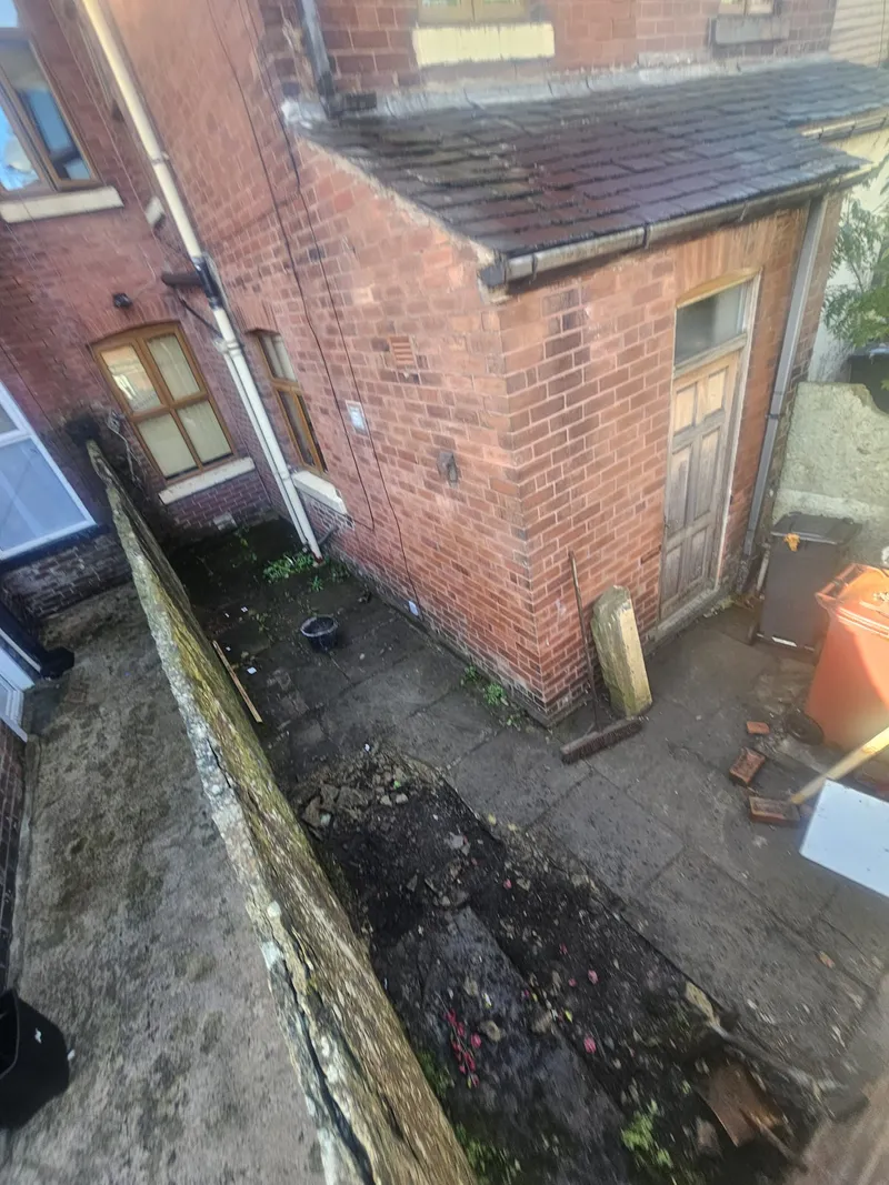 Back yard with soil and broken flags before work started