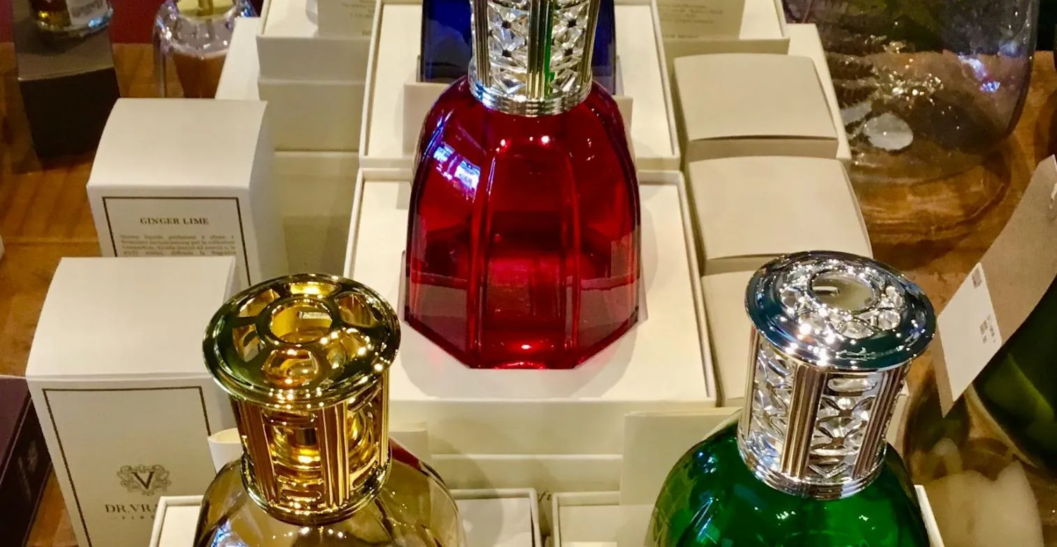 Display of colorful perfume bottles in decorative boxes, featuring gold, red, and green glass containers with ornate stoppers