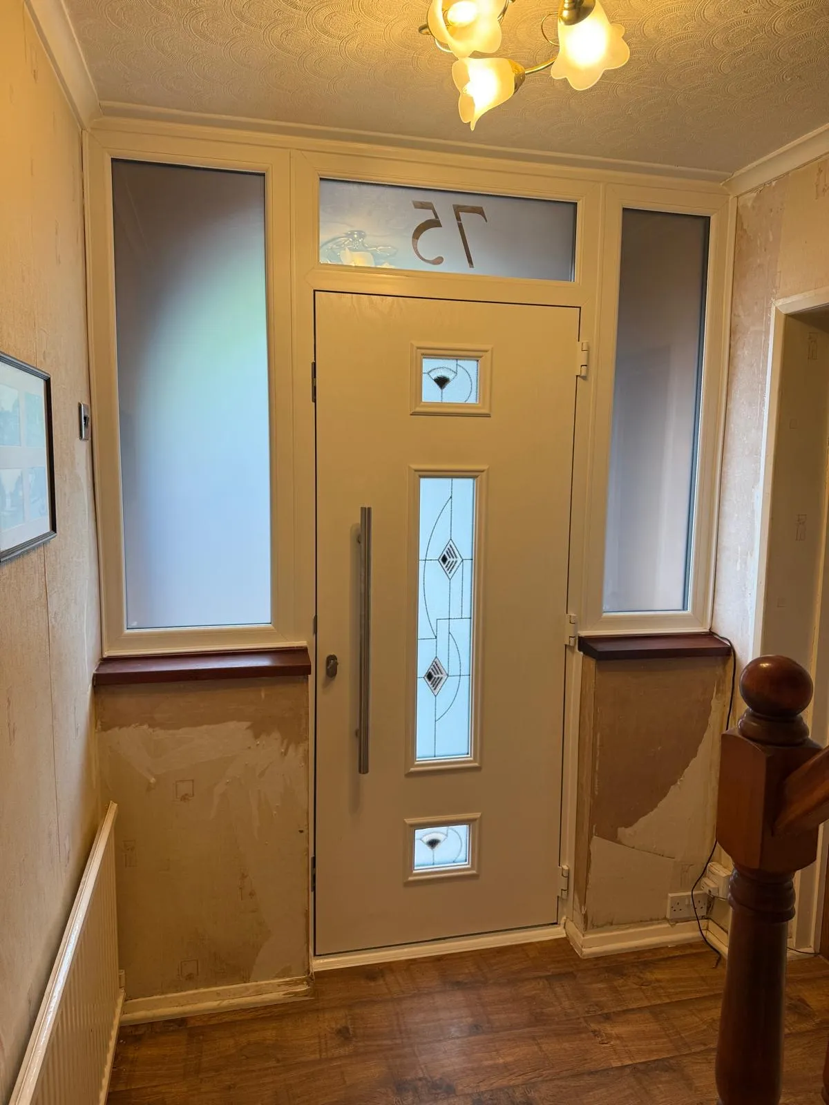 Interior view of a white composite door with decorative frosted glass panels and sidelights.